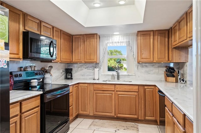 kitchen featuring tasteful backsplash, black appliances, a tray ceiling, and a sink