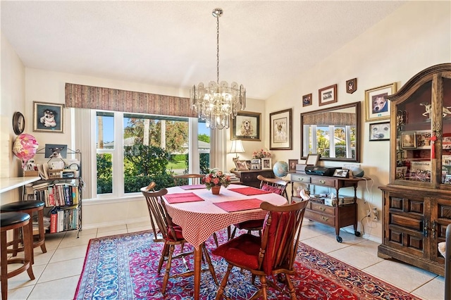 dining space with light tile patterned floors, a notable chandelier, baseboards, and lofted ceiling