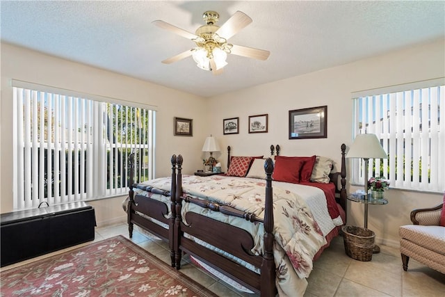 bedroom featuring light tile patterned floors, a ceiling fan, baseboards, and a textured ceiling