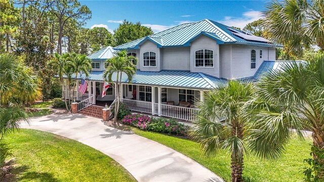 105 Charleston Oaks Dr, Port St Lucie, FL 34983 - coastal inspired home with covered porch, metal roof, a standing seam roof, and a front lawn