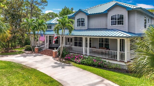 105 Charleston Oaks Dr, Port St Lucie, FL 34983 - view of front facade with a porch, metal roof, a standing seam roof, and a front yard