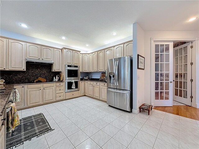 105 Charleston Oaks Dr, Port St Lucie, FL 34983 - kitchen with appliances with stainless steel finishes, french doors, dark countertops, under cabinet range hood, and light tile patterned floors