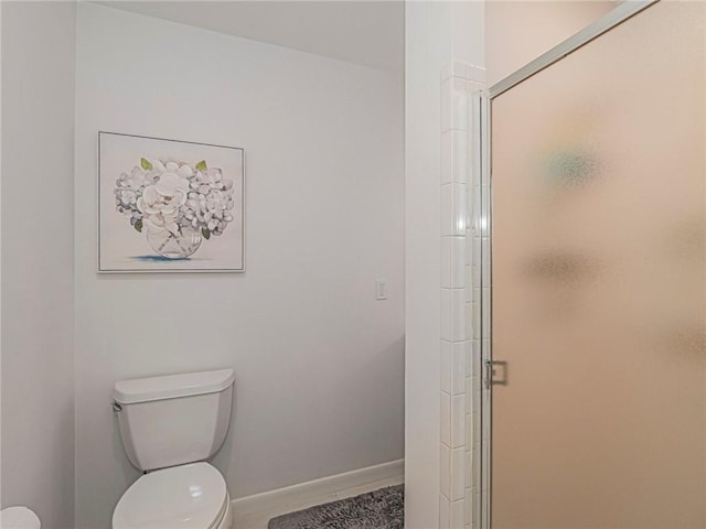 bathroom featuring a shower stall, toilet, and baseboards