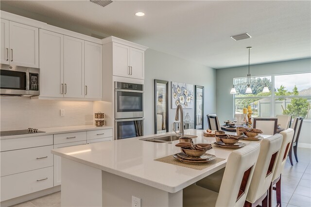 kitchen with sink, a kitchen island with sink, and appliances with stainless steel finishes