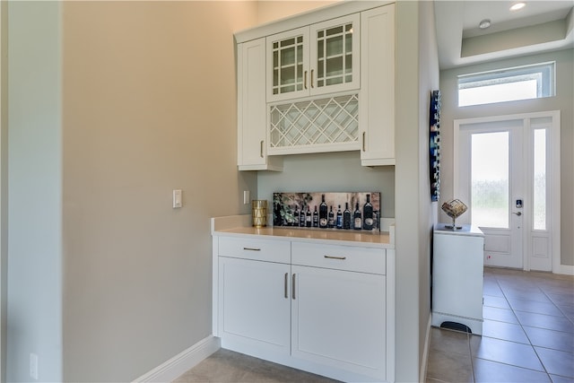 bar with white cabinets and light tile patterned flooring