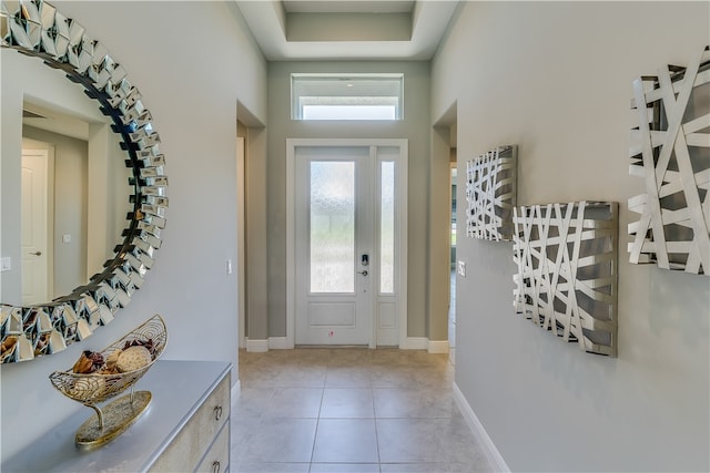 foyer with a tray ceiling, light tile patterned floors, and plenty of natural light