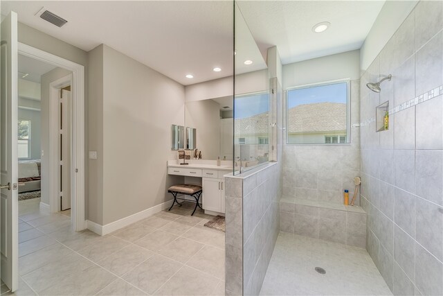 bathroom with tiled shower, tile patterned floors, and vanity