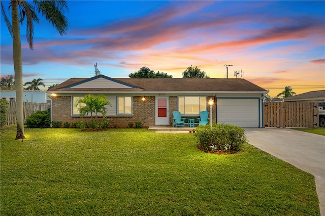 single story home featuring a garage and a lawn