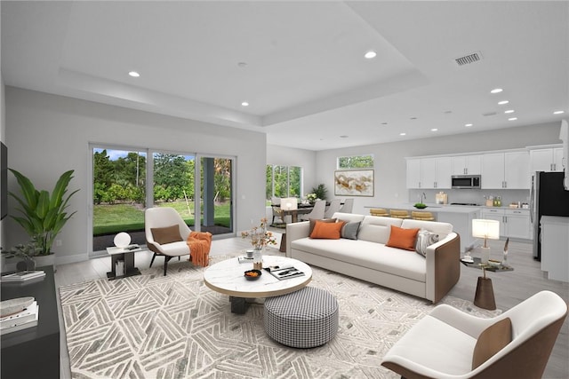 living room with a tray ceiling and light hardwood / wood-style flooring