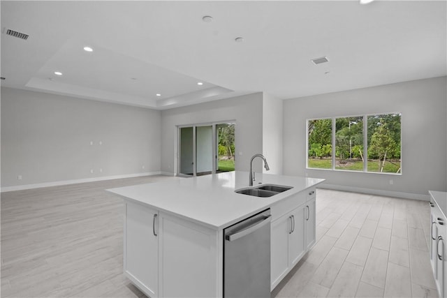 kitchen with sink, dishwasher, a raised ceiling, a kitchen island with sink, and white cabinets