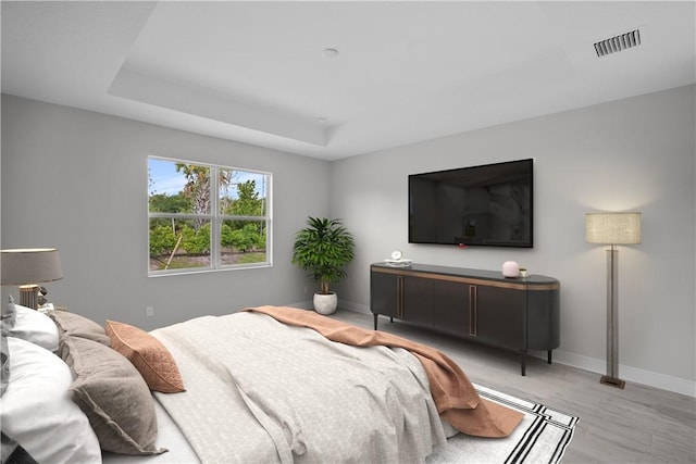 bedroom featuring light hardwood / wood-style floors and a tray ceiling