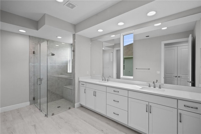 bathroom featuring a shower with door and vanity