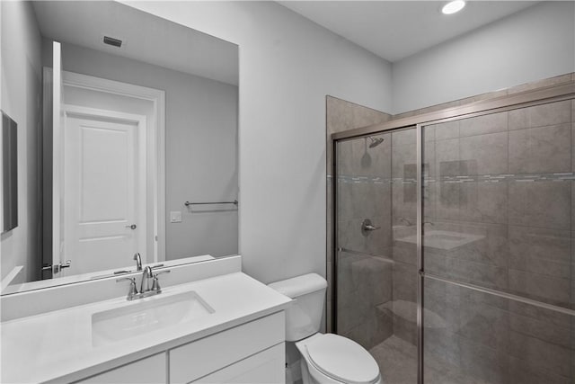 bathroom featuring vanity, an enclosed shower, and toilet