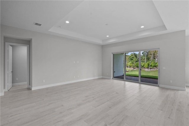 empty room featuring light hardwood / wood-style flooring and a raised ceiling