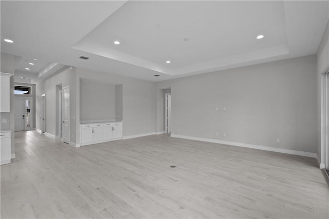 unfurnished living room with a raised ceiling and light hardwood / wood-style flooring