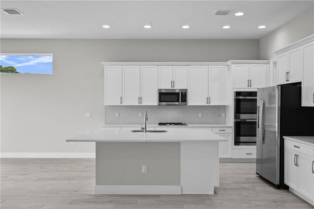 kitchen featuring stainless steel appliances, an island with sink, and white cabinets