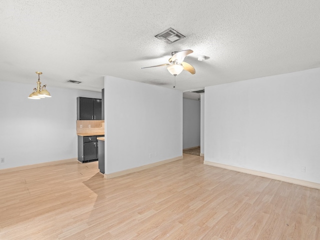 empty room with ceiling fan, light wood-type flooring, and a textured ceiling