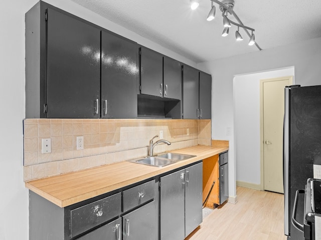 kitchen featuring decorative backsplash, stainless steel fridge, light hardwood / wood-style flooring, and sink