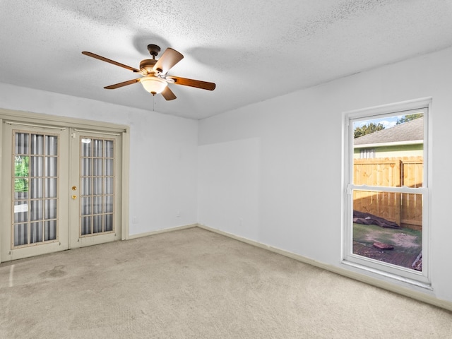 carpeted spare room featuring ceiling fan, french doors, and a textured ceiling