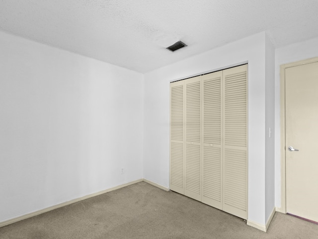 unfurnished bedroom featuring light carpet, a textured ceiling, and a closet