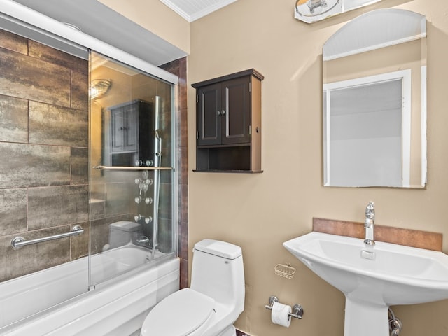 full bathroom featuring sink, bath / shower combo with glass door, and toilet