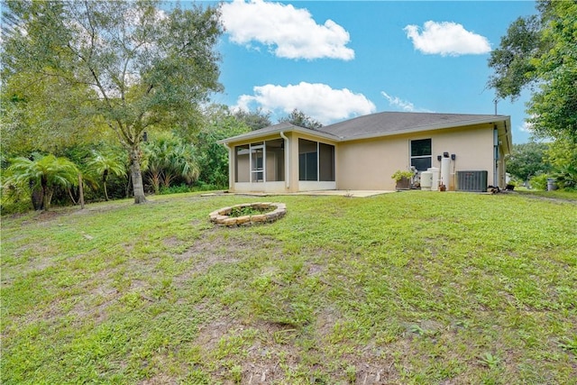 back of house featuring an outdoor fire pit, central AC, a yard, and a sunroom