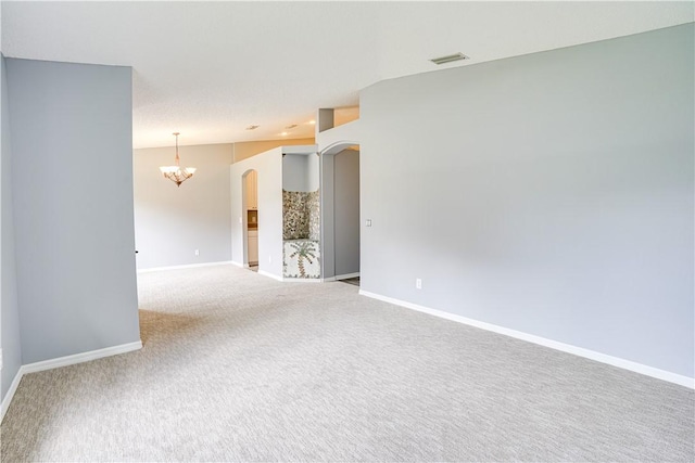 carpeted spare room featuring a notable chandelier