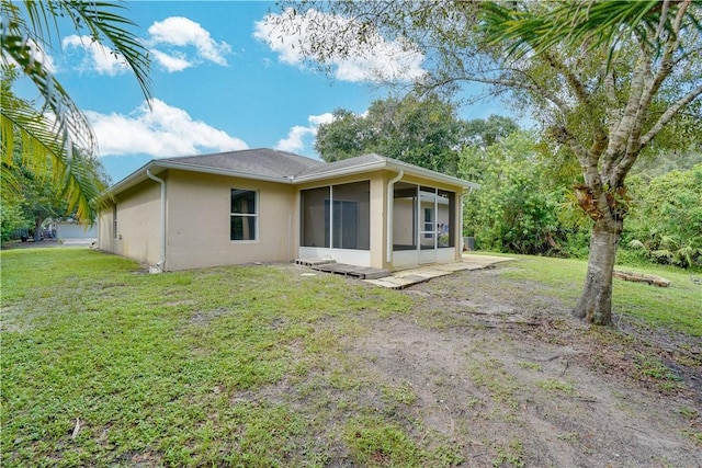 rear view of property with a sunroom and a lawn