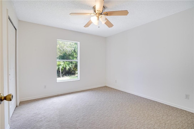 empty room featuring a textured ceiling, light colored carpet, and ceiling fan