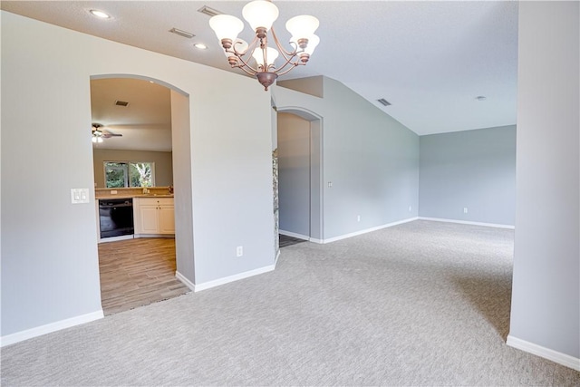 empty room with ceiling fan with notable chandelier and light colored carpet