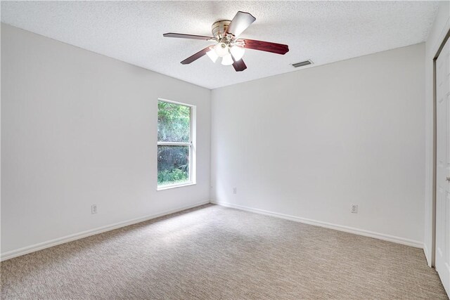 empty room featuring light colored carpet, a textured ceiling, and ceiling fan