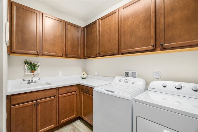 laundry room with light wood-style floors, cabinet space, independent washer and dryer, and a sink