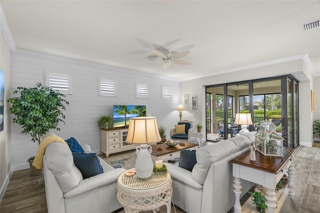 living area with visible vents, ornamental molding, ceiling fan, wood finished floors, and baseboards