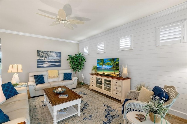 living area with a ceiling fan, crown molding, baseboards, and wood finished floors