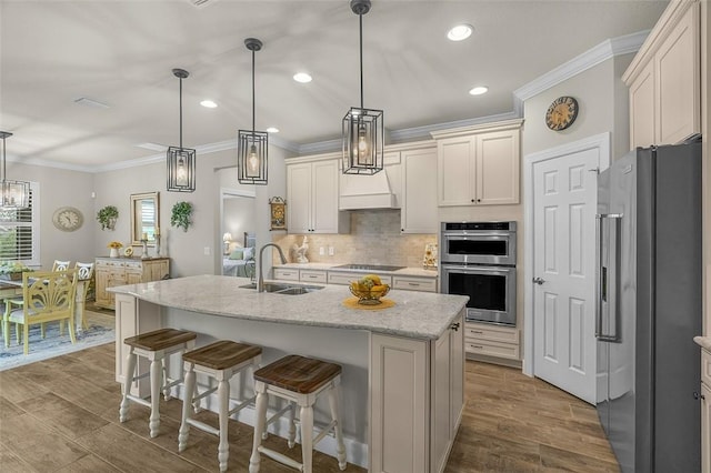 kitchen featuring crown molding, stainless steel appliances, backsplash, a sink, and wood finished floors