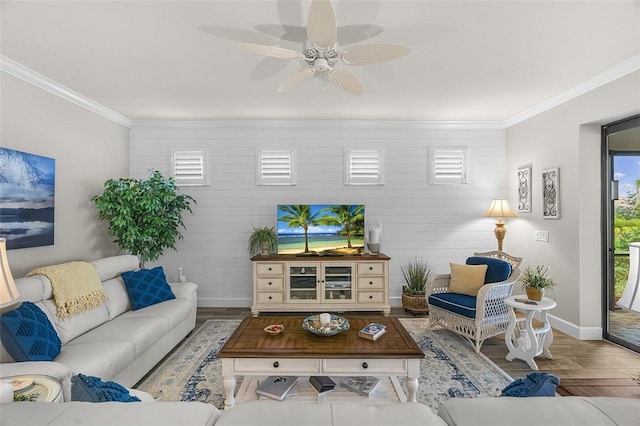 living area with ornamental molding, wood finished floors, a ceiling fan, and baseboards