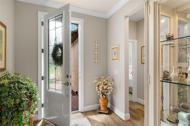 entrance foyer featuring ornamental molding, light wood-type flooring, and baseboards