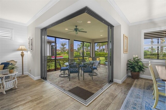 doorway featuring light wood-type flooring, crown molding, and baseboards