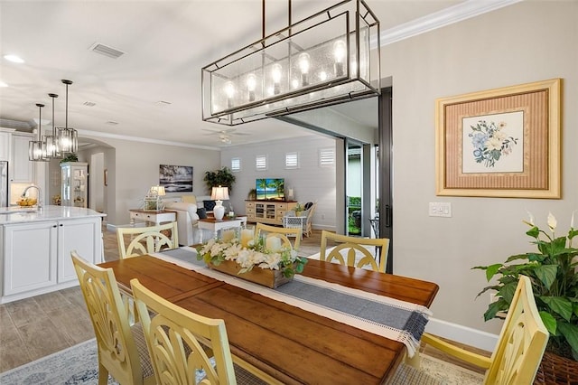 dining room with light wood-type flooring, baseboards, arched walkways, and crown molding