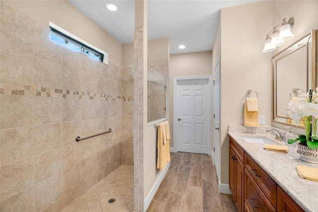 bathroom featuring double vanity, wood finished floors, a walk in shower, a sink, and recessed lighting