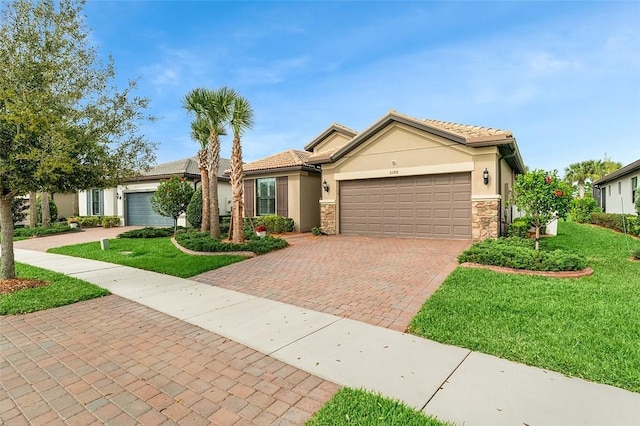 ranch-style home featuring a garage, stone siding, decorative driveway, stucco siding, and a front yard