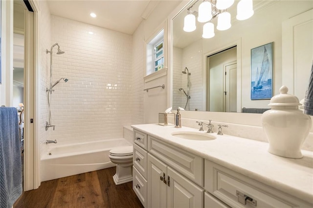 full bathroom featuring an inviting chandelier, toilet, hardwood / wood-style flooring, vanity, and tiled shower / bath