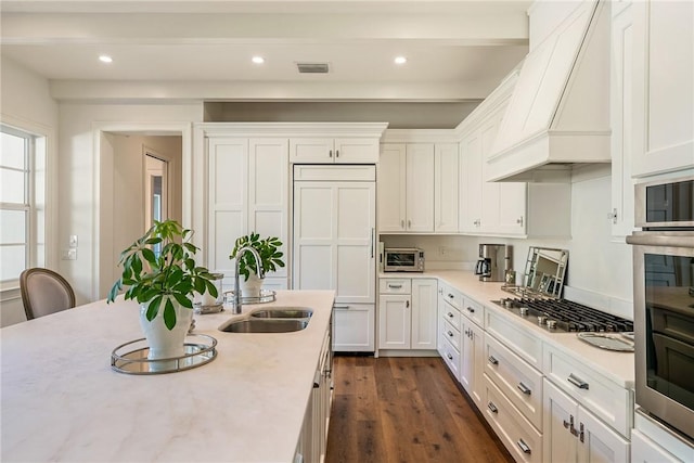 kitchen featuring custom exhaust hood, sink, paneled built in refrigerator, dark hardwood / wood-style floors, and white cabinetry