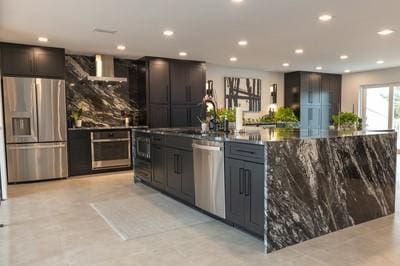 kitchen with appliances with stainless steel finishes, sink, decorative backsplash, and wall chimney range hood