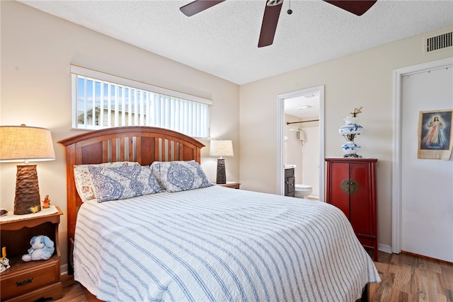 bedroom with ensuite bathroom, a textured ceiling, wood-type flooring, and ceiling fan