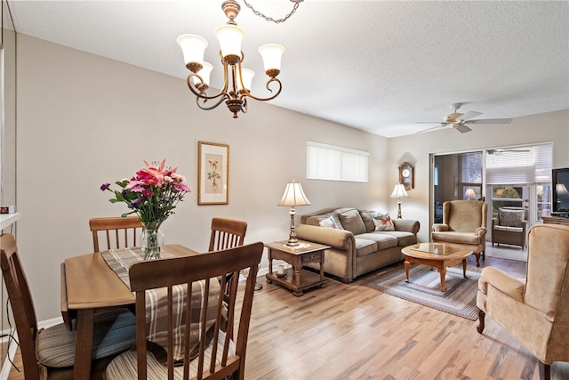 dining area featuring light wood-type flooring, a textured ceiling, and ceiling fan with notable chandelier