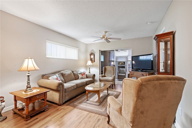 living room featuring ceiling fan, light hardwood / wood-style floors, a textured ceiling, and a healthy amount of sunlight