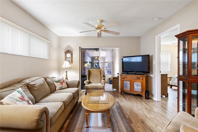 living room featuring light wood-type flooring, ceiling fan, and a healthy amount of sunlight