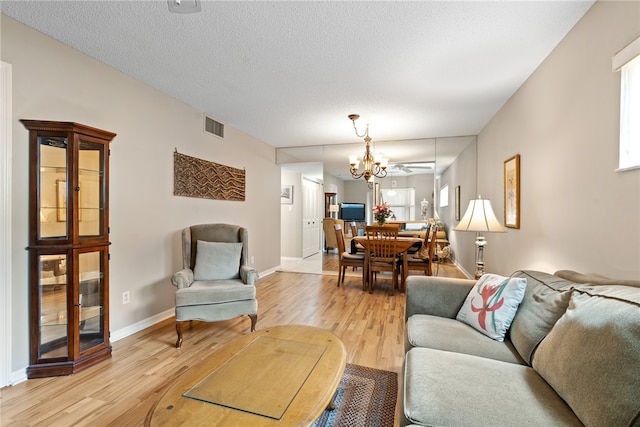 living room featuring an inviting chandelier, a textured ceiling, and light hardwood / wood-style flooring