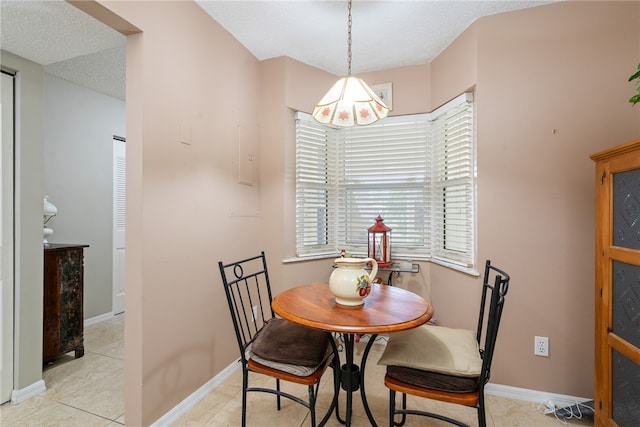 tiled dining space featuring an inviting chandelier and a textured ceiling